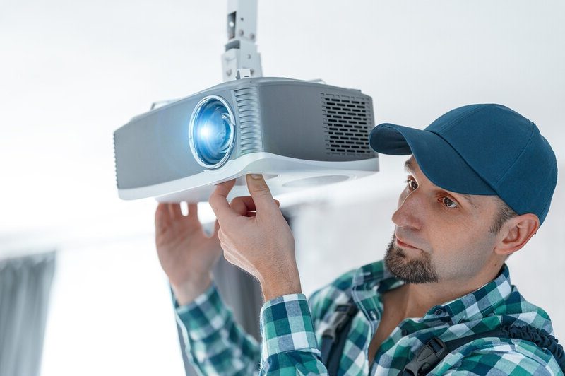 A specialist adjusts the focus of multimedia video projectors 
