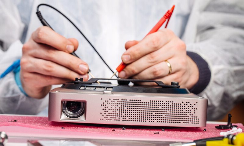 Close up hands of a service worker repairing a digital projector